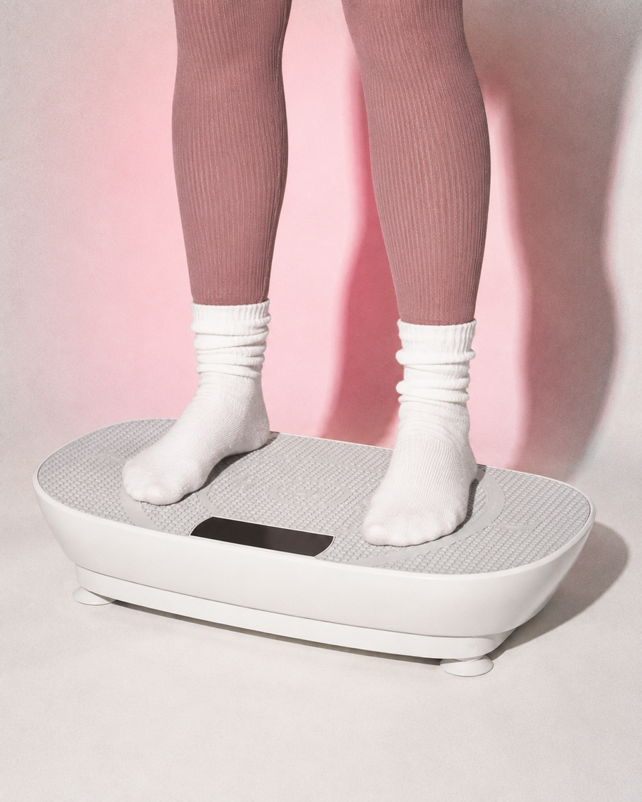 Standing on the REFORME Vibe+ vibration plate in white slouch socks