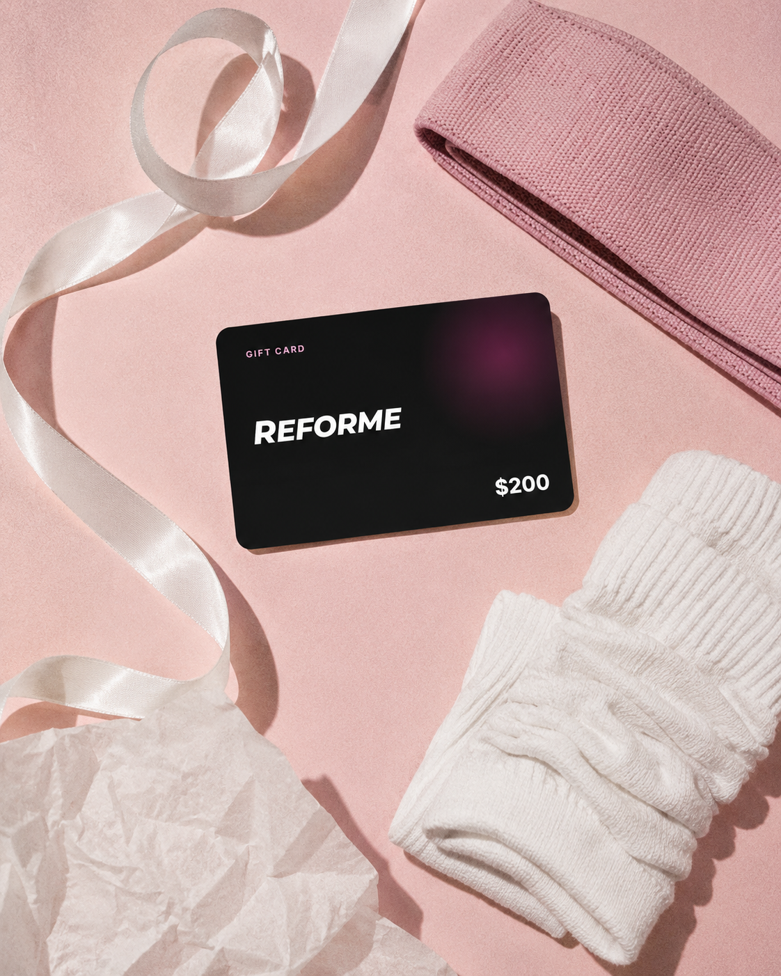 REFORME machine and accessories arranged as a gift with a ribbon on a pink backdrop